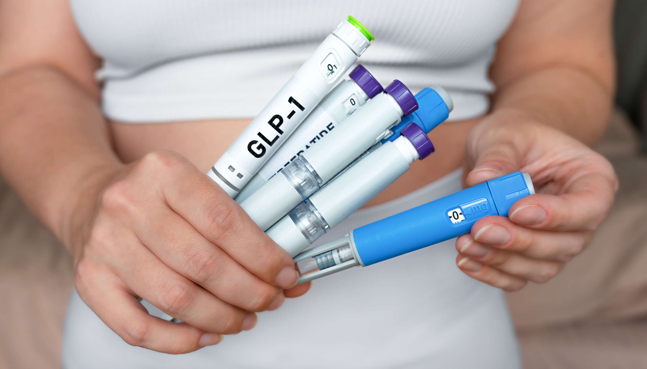 Woman holding several GLP-1 injectors