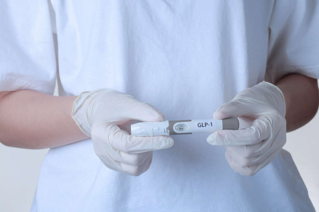 Medical professional holds GLP-1 injection pen confidently supporting patient on hopeful weight loss journey through modern clinical treatment